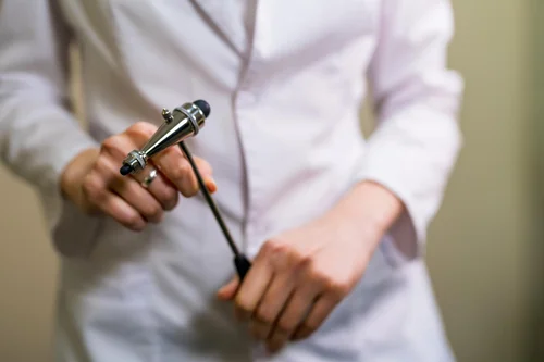 врач невролог держит в руке тромнер